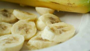 Close up of slices of fresh banana in a bowl on table . video