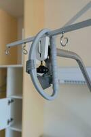 Gallow at the hospital bed in a hospital. Above hospital bed is hanging adaptive triangular metal frame. photo