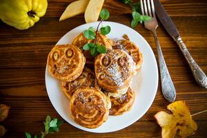 Cooked fried round pancakes with quince filling on a wooden table photo