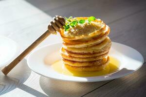 cooked sweet pancakes with honey in a plate photo