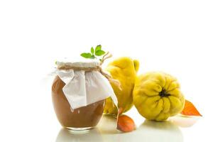 Ripe quince fruit with jam in a glass jar isolated on a white background. photo