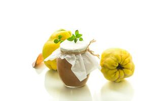 Ripe quince fruit with jam in a glass jar isolated on a white background. photo
