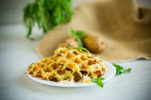 fried potato waffles with cheese in a plate on wooden table. photo