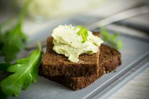 bread cheese spread with garlic and arugula on dark bread photo