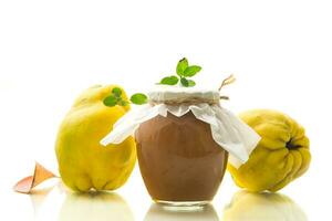 Ripe quince fruit with jam in a glass jar isolated on a white background. photo