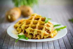 fried potato waffles with cheese in a plate on wooden table. photo