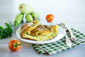 Fried omelet with zucchini, on a wooden table. photo