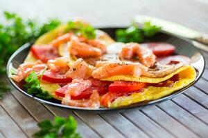 Fried omelette with tomatoes, vegetables and pieces of lightly salted red fish. photo