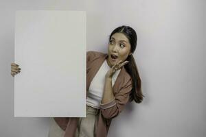 conmocionado joven asiático mujer empleado participación vacío blanco junta, aislado por blanco antecedentes foto
