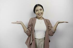 Excited Asian woman employee wearing cardigan pointing at the copy space beside her, isolated by white background photo