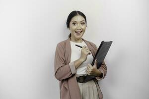 Smiling young Asian woman employee wearing cardigan while holding a clipboard, isolated by white background photo