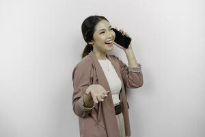 Smiling young Asian woman employee wearing cardigan while having a phone call, isolated by white background photo