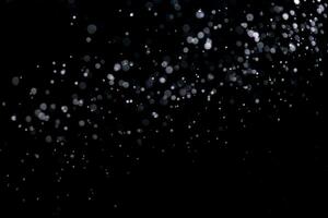 pequeño gotas de lluvia, nieve en un negro antecedentes. viento. natural antecedentes foto