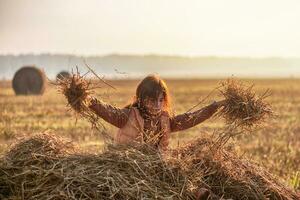 Cute teenage girl in field with wheat clippings and haystacks. morning, fog photo