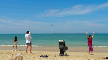 PHUKET, THAILAND FEBRUARY 18, 2023 Airplane landing at Phuket Airport. Plane flies overhead. Airliner flies over sea and beach. People tourists take pictures in front of an airplane video