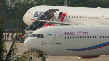 PHUKET, THAILAND JANUARY 23, 2023 Boeing 767 of Sunday Airlines at Phuket airport. Footage of airplane on the airfield. Background, passengers boarding an Azur Air plane video