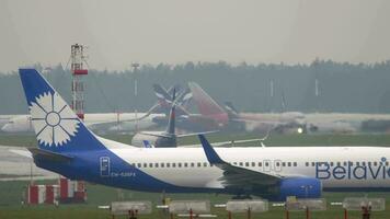 MOSCOW, RUSSIAN FEDERATION JULY 30, 2021 Passenger aircraft Boeing 737 of Belavia on the taxiway at Sheremetyevo airport, side view. Background, Aeroflot plane taking off video