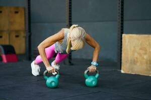 irreconocible deportista hacer ejercicio empujar UPS con pesas rusas en gimnasio foto