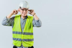 Young engineer covering ears isolated. Engineer man with ear pain. Concept of engineer covering his ears with pain expression photo