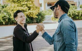 Two people shaking hands on the street. Two teenage friends shaking hands at each other outdoors. Concept of two friends greeting each other with handshake on the street. photo