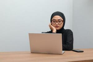 retrato de atractivo asiático hijab mujer trabajando en su ordenador portátil. musulmán niña sensación agotado y cansado. empleado y Lanza libre trabajador concepto. foto