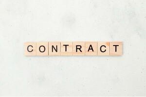 Top view of contract word on wooden cube letter block on white background. Business concept photo