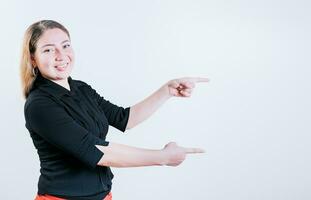 Happy latin woman pointing a promo isolated. Cheerful girl pointing an offer isolated. Beautiful young girl pointing to a banner to the side photo