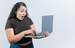 asombrado latín mujer utilizando ordenador portátil aislado. sorprendido niña mirando a un promoción en ordenador portátil pantalla foto