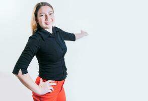 Smiling latin woman welcoming you isolated. Cheerful people pointing a promotion with her palm. Happy young girl pointing back presenting a product photo