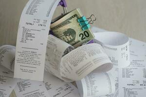 US dollars bunch in shopping trolley surrounded by many paper receipts photo