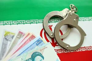 Iran flag and police handcuffs with iranian money bills rials. The concept of crime and offenses photo