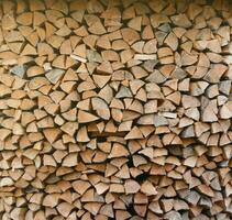 Firewood stacked near the wooden wall of old hut. Many chopped logs of firewood photo