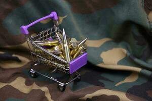 Rifle cartridges in small shopping cart. Big caliber ammo cartridges with a small shopping basket photo