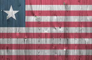 Liberia flag depicted in bright paint colors on old wooden wall. Textured banner on rough background photo