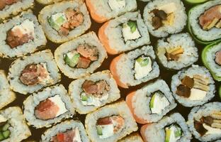 Close-up of a lot of sushi rolls with different fillings. Macro shot of cooked classic Japanese food. Background image photo