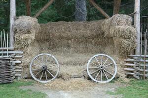 Place with stacks of hay cubes and rustic wooden wheels of old cart photo
