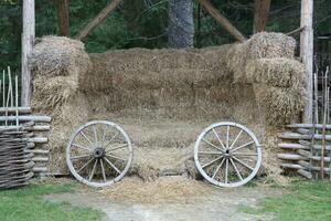 Place with stacks of hay cubes and rustic wooden wheels of old cart photo