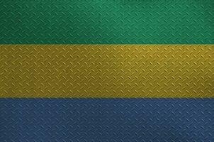 Gabon flag depicted in paint colors on old brushed metal plate or wall closeup. Textured banner on rough background photo