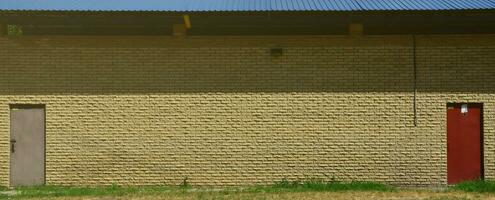Texture of brick wall from relief stones under bright sunlight with two metal doors photo