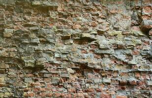 Very old brick stone wall of castle or fortress of 18th century. Full frame wall with obsolete dirty and cracked bricks photo