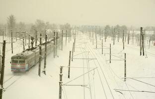 A long train of passenger cars is moving along the railway track. Railway landscape in winter after snowfall photo