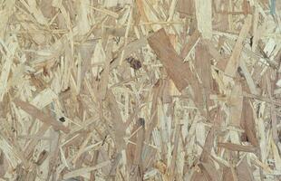 OSB boards made of brown wood chips sanded into a wooden background. Top view of OSB wood veneer background surface photo