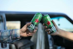 KHARKOV, UKRAINE - JULY 31, 2021 Green tin cans of Heineken pale lager beer in men hands photo