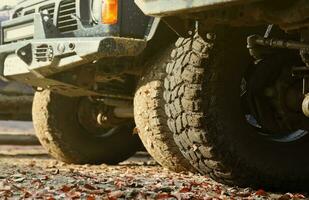 Wheel closeup in a countryside landscape with a mud road. Off-road 4x4 suv automobile with ditry body after drive in muddy road photo