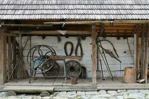 Collection of planers and retro wood saws hang on a wooden wall near an old house. Carpenters plane and other things on wall photo