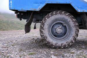 Wheel closeup in a countryside landscape with a mud road. Off-road 4x4 suv automobile with ditry body after drive in muddy road photo