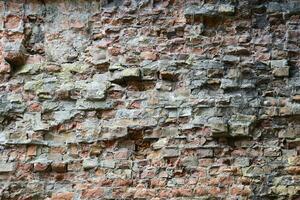 Very old brick stone wall of castle or fortress of 18th century. Full frame wall with obsolete dirty and cracked bricks photo