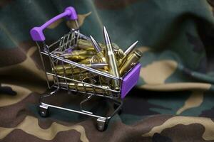 Rifle cartridges in small shopping cart. Big caliber ammo cartridges with a small shopping basket photo