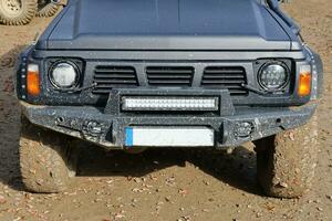 Automobile in a countryside landscape with a mud road. Off-road 4x4 suv automobile with ditry body after drive in muddy road photo