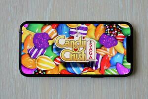 Candy Crush Saga mobile iOS game on iPhone 15 smartphone screen on wooden table during mobile gameplay photo